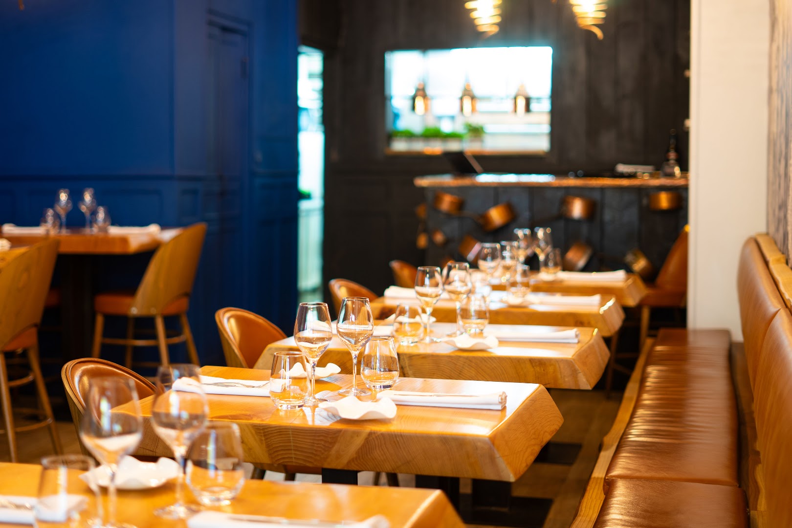 La salle du Loup avec tables en bois, banquettes et verres dressés