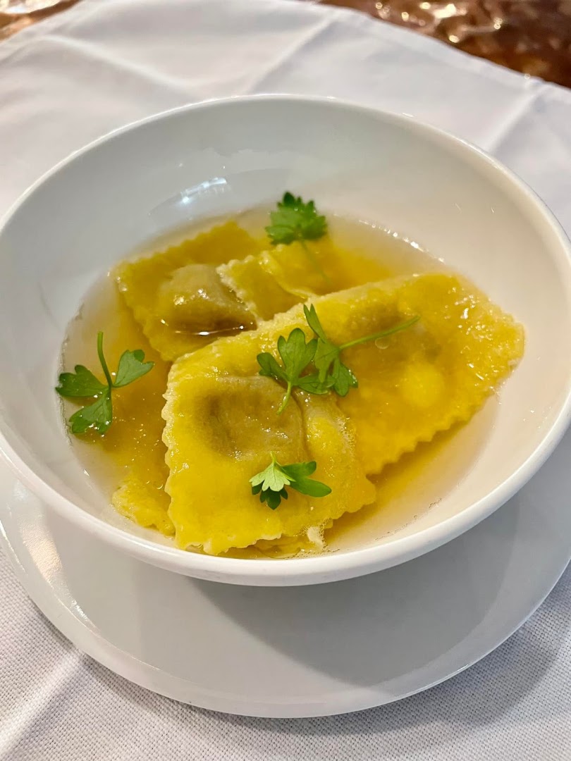 Des pâtes farcies jaunes dans un bouillon clair avec des herbes