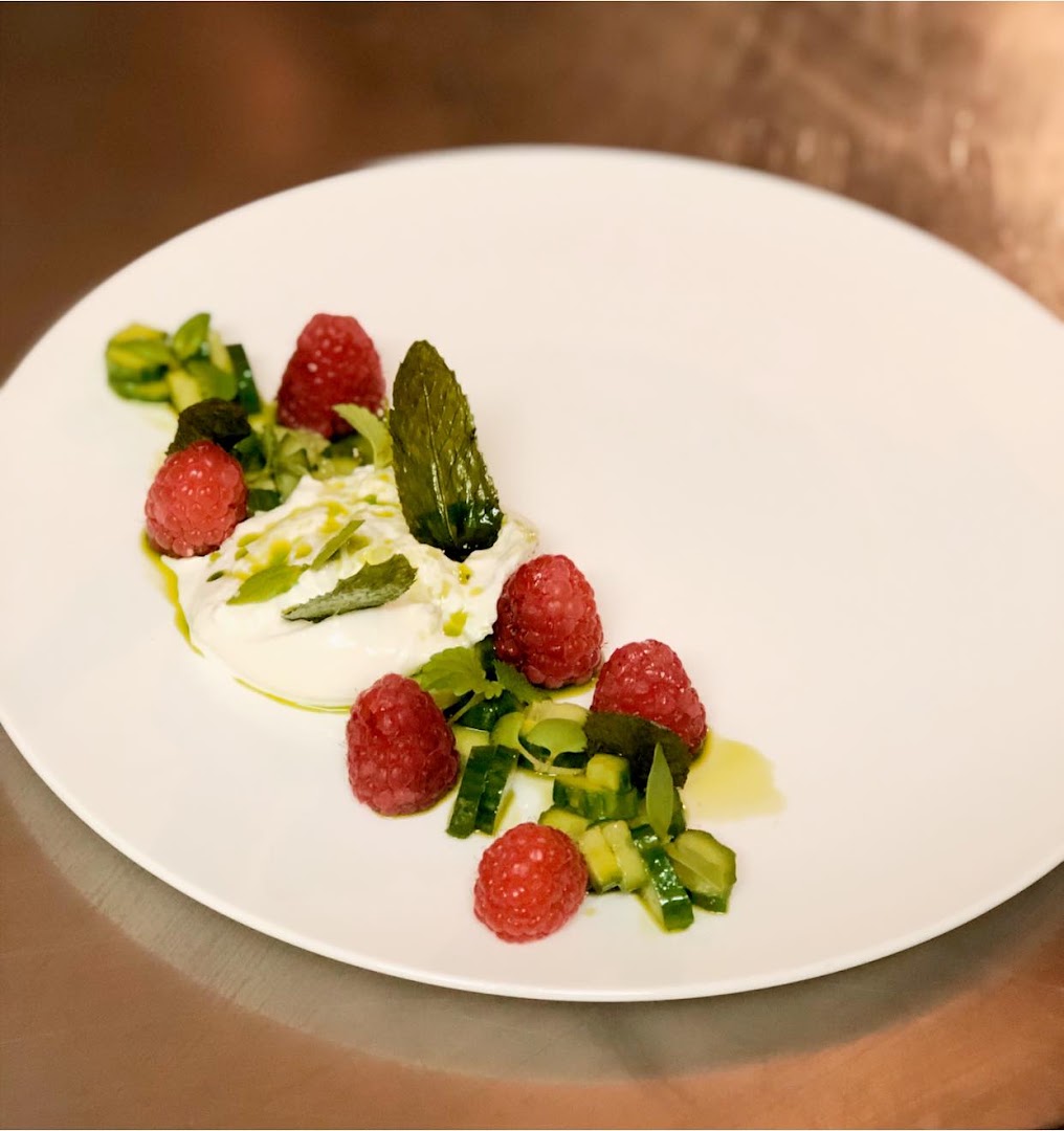 Une assiette de framboises, éléments verts et crème blanche